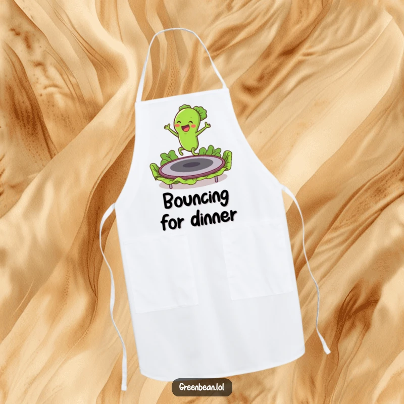 Funny apron illustrating an excited green bean character bouncing energetically on a lettuce trampoline, ready for kitchen fun.